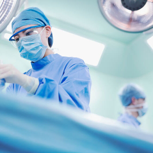 Female Asian Chinese woman nurse OR staff surgeon holding surgical anesthesia mask tube dressed in safety gown scrubs and performing operation in operating room medical facility hospital healthcare